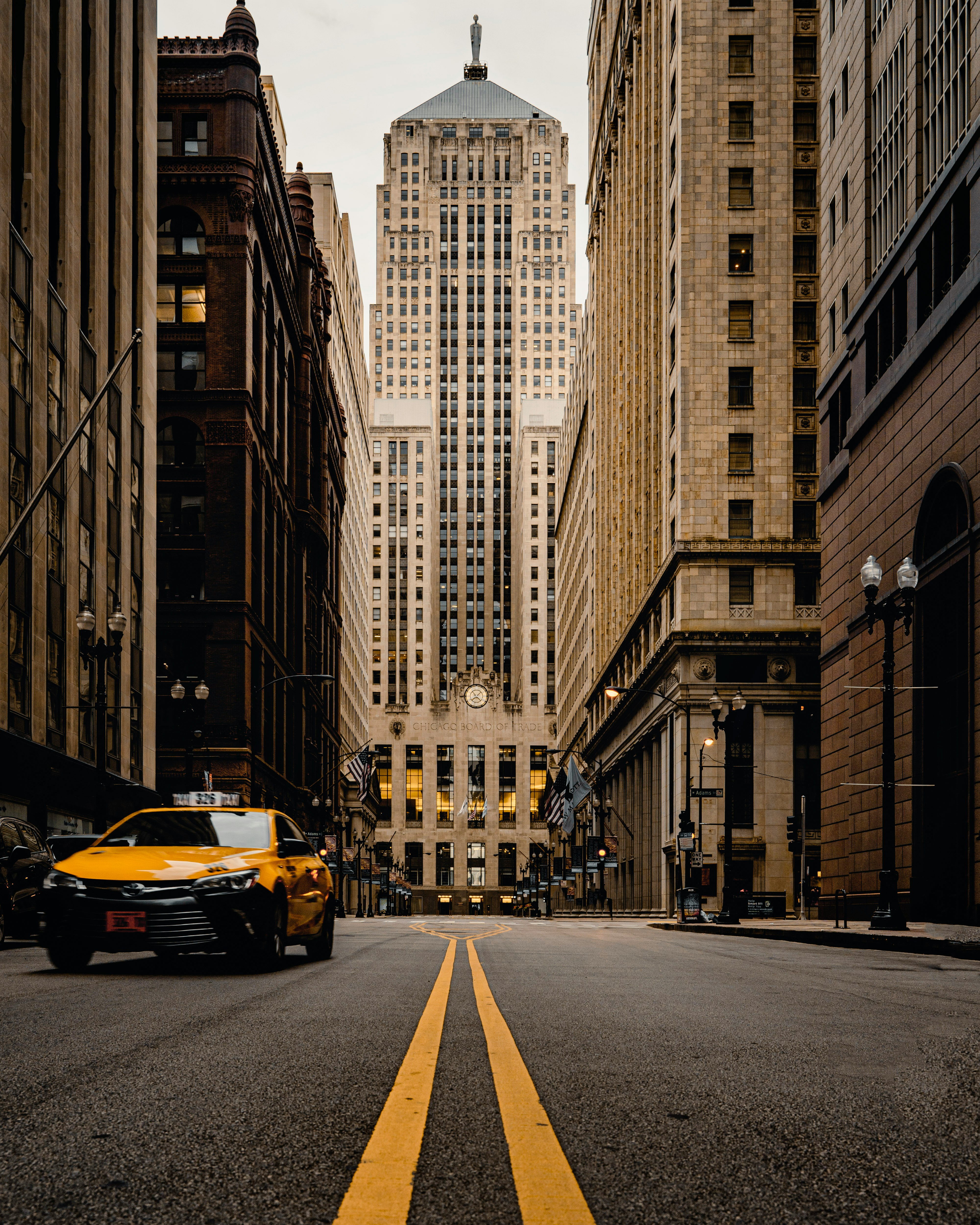 yellow car on road in between high rise buildings during daytime